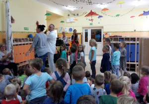 Prowadzący z jedną nauczycielek oraz grupą dzieci ustawieni w parach ćwiczą krok poloneza.