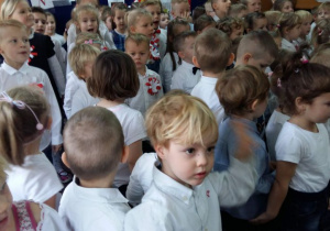 Przedszkolaki ubrane w odświętne stroje i śpiewają hymn Polski.