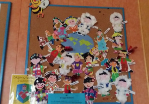 Prace plastyczne na tablicy grupy V, przedstawiające dzieci z różnych krajów.