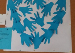 Prace plastyczne na tablicy grupy IV, przedstawiająca ręce w kolorze błękitnym, ułożone w kształcie serca.
