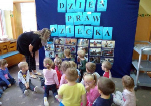 Dzieci z grupy II przed dekoracją ze zdjęciami, przedstawiającymi prawa dziecka.