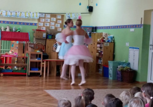 2 baletnice na scenie. Prezentują figury baletowe.