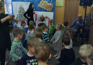 Dzieci bawią się podczas zabawy mikołajkowej w parach. Nauczycielka robi zdjęcie dzieciom, druga z pań stoi przy dekoracji świątecznej.