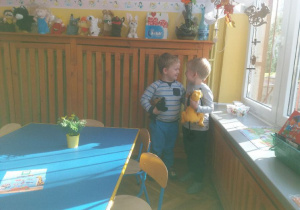 2 chłopcy bawią się pluszowymi maskotkami. W tle widoczne są meble przedszkolne i zabawki