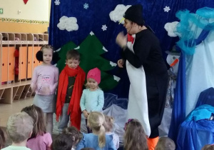 Aktorka przebrana za pingwina zachęca dzieci posiadające rekwizyty zimowe do odegrania krótkich scenek.