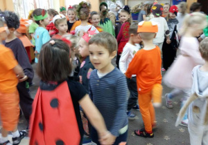 Przedszkolaki ubrane w stroje jesienne tańcza na balu jesieni.