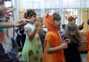 Dzieci w strojach jesiennych tańcza w rytm muzyki.