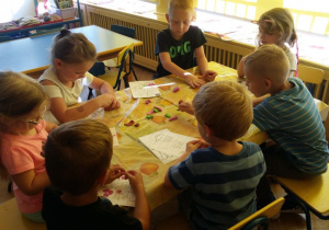 Dzieci lepią z plasteliny przy stoliku.