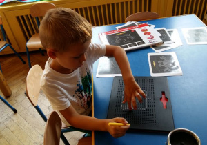 Chłopiec przy stoliku z tablicą magnetyczną.
