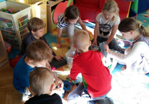 Dzieci bawią się na dywanie klockami.