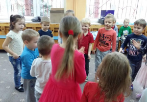 Dzieci stoją w kole podczas zabawy mikołajkowej
