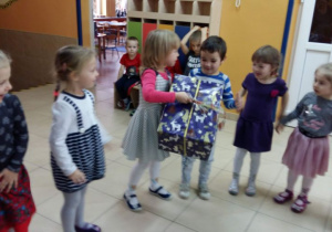 Dzieci biorą udział w konkursie. Podają sobie prezent z rąk do rąk.
