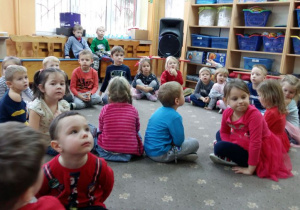 Dzieci siedzą na dywanie podczas zabawy mikołajkowej