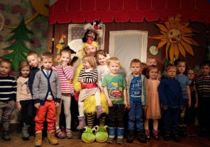 Dzieci na scenie teatru pozują do zdjęcia z aktorem.