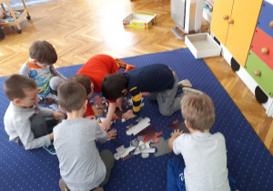 Dzieci układają puzzle na dywanie