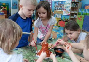 Dzieci malują brązową farbą wulkan, zrobiony z masy solnej