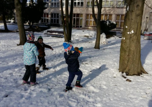 Zabawa dzieci na śniegu. Rzuty kulkami śnieznymi do drzewa.