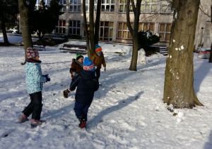 Zabawa dzieci na śniegu. Rzuty kulkami śnieznymi do drzewa.