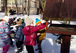 Dzieci zimą wysypują do karmnika pokarm dla ptaków