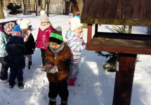 Dzieci zimą wysypują do karmnika pokarm dla ptaków