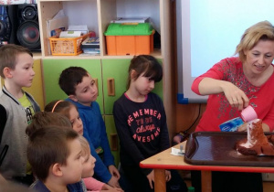 Dzieci patrzą jak nauczycielka wykonuje doświadczenie z wulkanem.