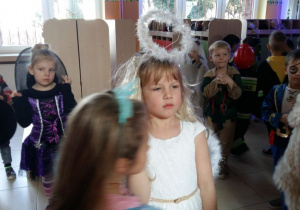 Dzieci przebrane w stroje karnawałowe bawią się na balu. W tle widać szafki w szatni przedszkolnej.