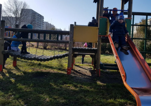 Dzieci bawią się na zjeżdżalni w ogrodzie przedszkolnym.