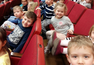 Dzieci siedzą na widowni i oczekują na przedstawienie.