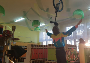 Akrobata w szatni przedszkolnej prezentuje pokaz ekwilibrystyki: balans monocyklem
