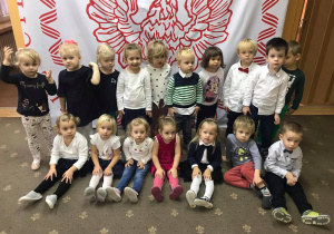 Dzieci z grupy I na tle biało - czerwonej dekoracji.