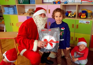 Chłopiec pozuje z Mikołajem i prezentem