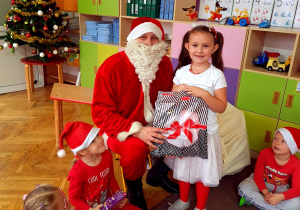 Dziewczynka pozuje z Mikołajem i prezentem