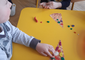 Dzieci wykonują pracę plastyczną- dekorują kawałek pizzy