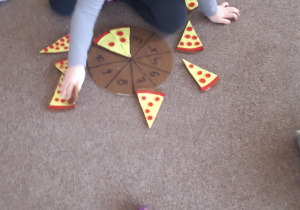 Dziewczynka układa kawałki pizzy dopasowując właściwą ilość elementów do cyfry