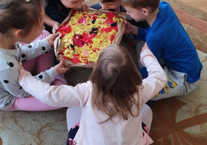 Dzieci trzymają wykonaną przez siebie pracę plastyczną- pizzę