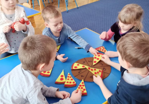 Dzieci układają kawałki pizzy dopasowując właściwą ilość elementów do cyfry