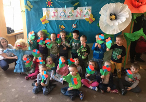 Dzieci pozują do zdjęcia z wykonanymi papierowymi kwiatami i Marzanną