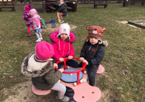 Dzieci siedzą na bujanej zabawce ogrodowej