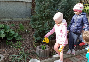 Dzieci podlewają rośliny w ogrodzie przedszkolnym