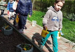 Dzieci podlewają rośliny w ogrodzie przedszkolnym
