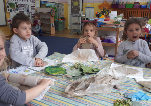 Dzieci siedzące przy stole, tworzą prace plastyczną z gliny