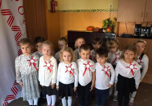 Dzieci ubrane w odświętne stroje, śpiewają hymn Polski
