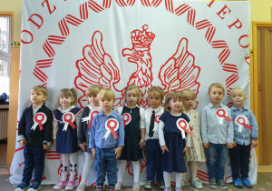 Dzieci ubrane w odświętne stroje, śpiewają hymn Polski