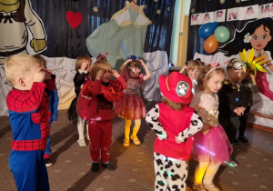 Dzieci przebrane w stroje karnawałowe tańczą na balu