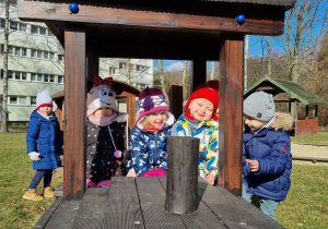 Dzieci z grupy pierwszej siedzące w "drewnianym pociągu" w ogrodzie przedszkolnym