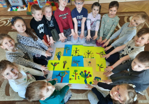 Dzieci pozują do zdjęcia przy pracach plastycznych, przedstawiajacych drzewa