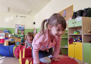 Dzieci pokonują tor przeszkód z materacy, tunelu.