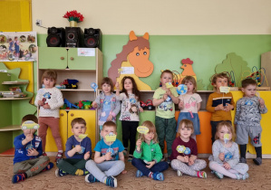 Dzieci pozują do zdjęcia, trzymają w rękach emblematy związane z dbaniem o środowisko