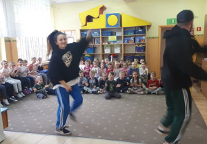 Dzieci siedzą na dywanie i oglądają pokaz tańca hip-hop