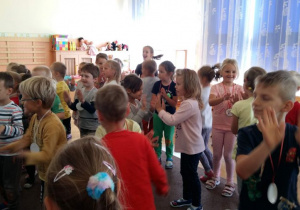 Dzieci z grupy czwartej i piątek tańczą w parach w sali przedszkolnej.